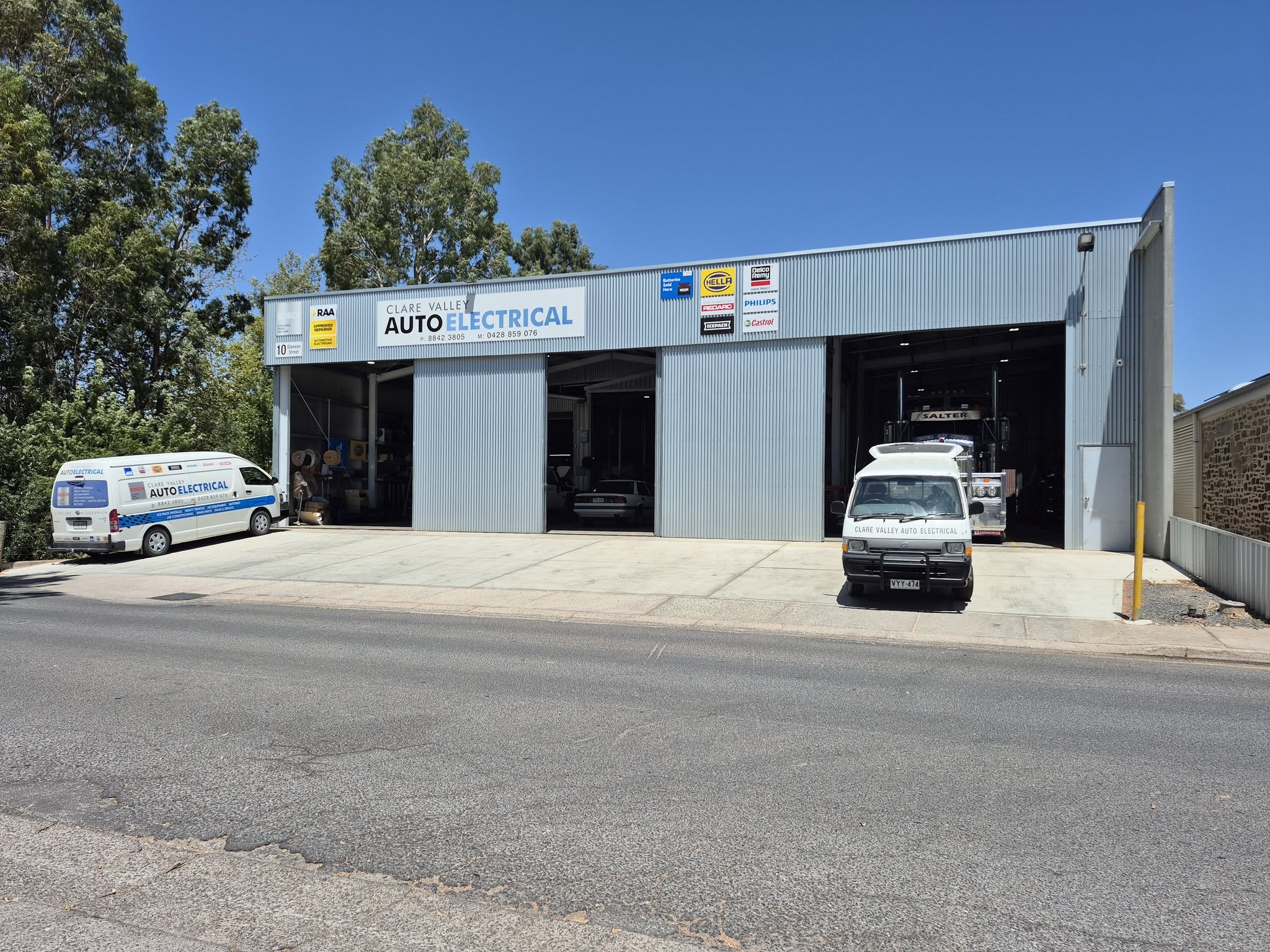 The Clare Valley Auto Electrical shed on a clear day with all three workshop bays open and both service vans out the front